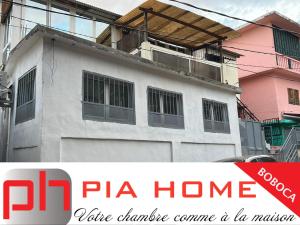 un bâtiment blanc avec un panneau indiquant la maison de pizza dans l'établissement PIA HOME La Pompe, à Mamoudzou