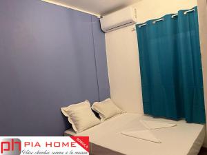 a small room with a bed with a blue shower curtain at PIA HOME La Pompe in Mamoudzou