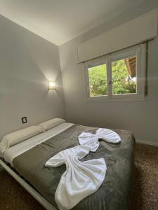 a bedroom with a bed with white sheets and a window at Panorama Villa Gesell in Villa Gesell