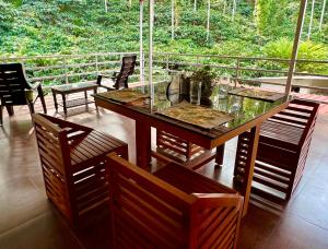 a table and chairs on a porch with a view of trees at Green Castle in Gonikoppal