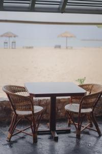 a table with two chairs and an umbrella on the beach at Bann Pae Cabana Hotel And Resort in Klaeng
