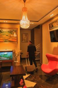 a man walking through a living room with a chandelier at Tree Love Temanggung Hotel in Parakan