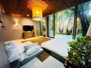 a bedroom with a bed and a couch and a tv at Luz de Luna Tulum in Yaxiik in Tulum