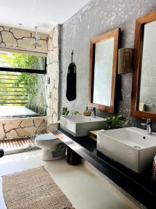 a bathroom with two sinks and a toilet and a mirror at Luz de Luna Tulum in Yaxiik in Tulum