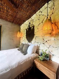 a bedroom with a stone wall and a bed with pillows at Luz de Luna Tulum Villa in Tulum +29 photos