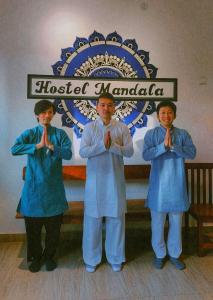 three men in blue robes praying in front of a sign at Hostel Mandala in Anjuna