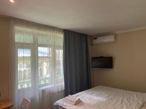 a bedroom with a bed and a large window at OSH ART Meergul in Osh