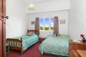a bedroom with two beds and a window at Early Settler Homestead - Waipu Holiday Home in Waipu