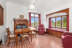 a dining room with a table and a fireplace at Early Settler Homestead - Waipu Holiday Home in Waipu