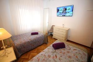 マドリードにあるAlojamiento Adelfasのベッドルーム1室(ベッド2台、壁掛けテレビ付)