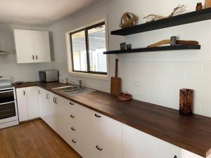 a kitchen with white cabinets and a wooden counter top at Hardwicke Hideaway in Port Minlacowie +9 photos