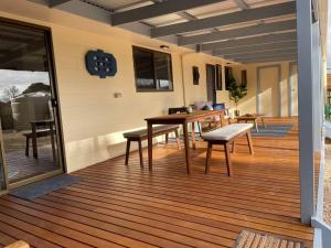 a porch with a table and benches on a deck at Hardwicke Hideaway in Port Minlacowie