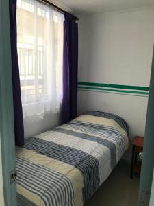 a small bedroom with a bed and a window at Departamento La Serena in La Serena
