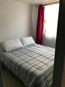 a bed in a white room with a window at Departamento La Serena in La Serena