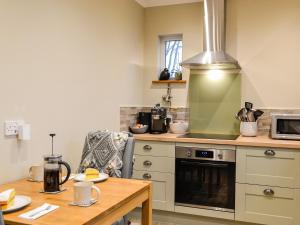 a kitchen with a stove and a wooden table at Cotlea East Cottage in Alyth