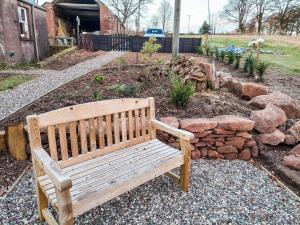 una panchina di legno seduta in un giardino con rocce di Cotlea East Cottage ad Alyth