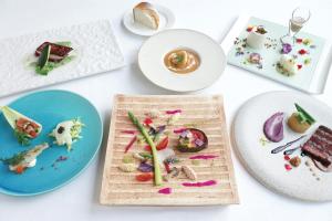 Biały stół z talerzami żywności w obiekcie EM Wellness Kurashinohakko Lifestyle Resort w mieście Kitanakagusuku