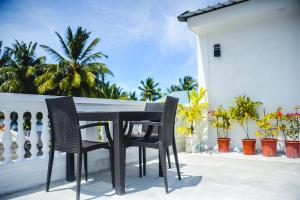 Una mesa y sillas en un balcón con palmeras. en Asseyri Guest House, en Maradhoofeydhoo