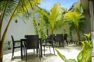 Un grupo de sillas y mesas negras y palmeras. en Asseyri Guest House, en Maradhoofeydhoo