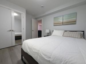 a white bedroom with a large bed and a mirror at Modern & Luxurious Suites in Surrey in Surrey