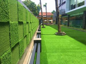 a bench in front of a green wall at Yasmin Hotel Karawaci in Tangerang