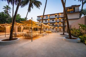 un patio del hotel con mesas, sillas y palmeras en Zostel Goa, Morjim, en Morjim