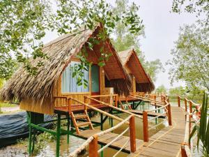une maison sur l'eau avec une terrasse en bois dans l'établissement Coco Island Cồn Phụng, à Ben Tre