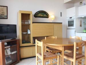 uma cozinha com uma mesa de madeira com cadeiras e uma televisão em Appartement La Baule, 1 pièce, 4 personnes - FR-1-245-133 em La Baule