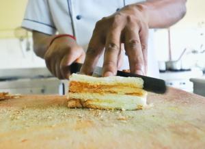 a person cutting a piece of cake with a knife at Velvet Rooms By 29bungalow in Lonavala