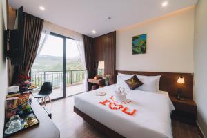 GREENECO DA LAT HOTEL - Khách sạn Green Eco Đà Lạt في دالات: غرفه فندقيه بسرير وشرفه