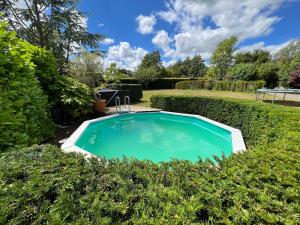 una piscina en un jardín con arbustos en 1 Northside Cottages en Godalming