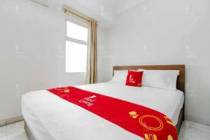 Una cama con una manta roja en una habitación en RedLiving Apartemen Margonda Residence 2 - Tower 2 en Pondokcina