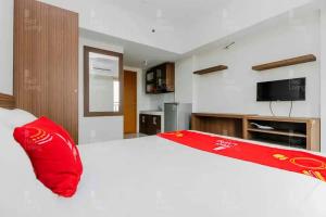 1 dormitorio con cama blanca grande y almohada roja en RedLiving Apartemen Margonda Residence 2 - Tower 2, en Pondokcina