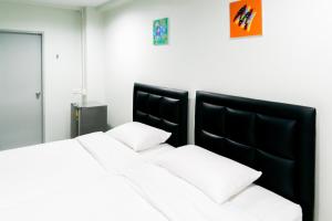 a bedroom with two beds and a black headboard at Suksomboon Residence in Bangkok