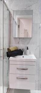 bagno bianco con lavandino e specchio di London gateway studio flat a Borehamwood
