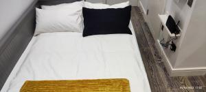uma cama com uma almofada preta e almofadas brancas em London gateway studio flat em Borehamwood