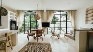 a living room with a table and chairs and windows at Villa Sakinah Canggu in Canggu