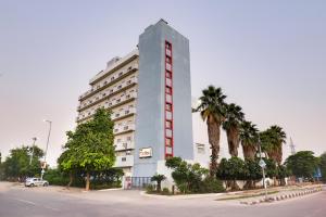 新德里Red Fox by Lemon Tree Hotels, East Delhi的一栋高大的白色建筑，前面有棕榈树