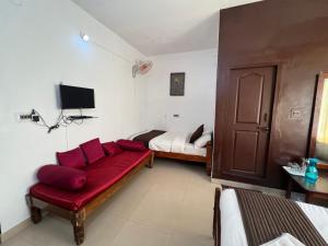 a living room with a red couch and two beds at Hotel Caveri Inn in Madikeri