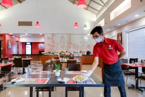 新德里Red Fox by Lemon Tree Hotels, East Delhi的蒙面人在餐厅桌子上准备食物