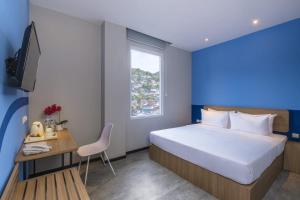 a bedroom with a bed and a desk and a window at Rumaruma Farvet Residence @ Ambon in Ambon