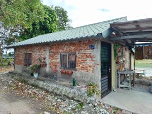 une maison en briques avec une véranda et une porte dans l'établissement 池上鄉屋 寵物友善民宿, à Chishang