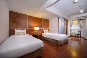 a hotel room with two beds and a table at Estia Chiangmai -SHA Plus in Chiang Mai