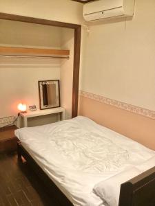 ein Schlafzimmer mit einem weißen Bett in einem Zimmer in der Unterkunft IZA Kamakura Guest House and Bar in Kamakura