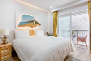 a bedroom with a large white bed and a balcony at Xlendi Central Apartment in Xlendi
