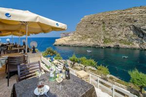 a table with drinks and an umbrella next to the water at Xlendi Central Apartment in Xlendi