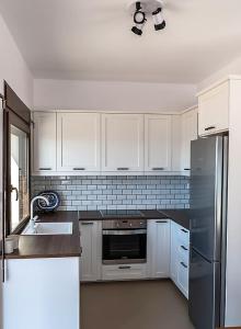 a kitchen with white cabinets and a stainless steel refrigerator at Seaview Villa in Tavari