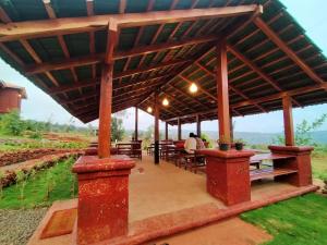 a large wooden pavilion with tables and benches at Holygram Krushi Paryatan in Panchgani
