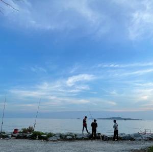 un gruppo di tre uomini che pescano sulla spiaggia di Bayu Laut Homestay a Malacca