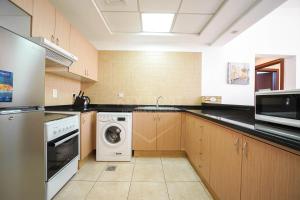a large kitchen with a washer and dryer in it at KeyHost - Minimalist 1BR - Dubai Sports City - K1020 in Dubai